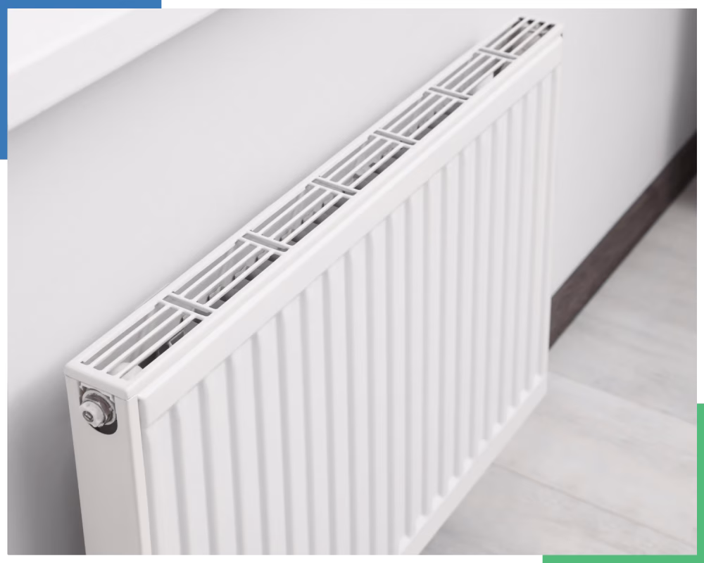 A radiator, a component of a central heating system, is shown from a high angle in a room with a light wood floor. The radiator is white with a slatted top and a control valve on its side.
