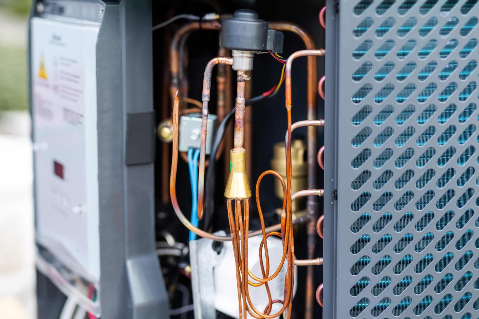 Close-up view of the internal copper piping, wiring, and components inside a modern water heater, showing intricate details of its heating and circulation system.